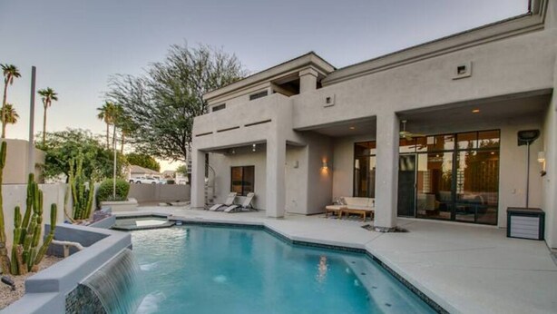 A modern house with a swimming pool, outdoor seating, and a patio area.
