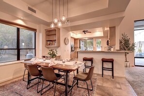 A dining area with a wooden table, chairs, and hanging pendant lights.