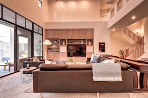 A modern living room with a large sofa, a flat-screen TV, and built-in wooden cabinets.