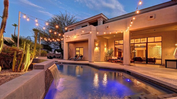 A modern pool area with a clear pool, surrounded by a patio with lounge chairs and string lights. - Casa Buena—Luxurious Retreat w/2 Masters & Views! (Phoenix)