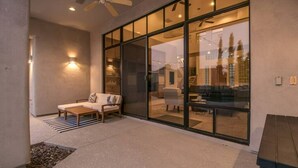 A modern outdoor patio with a sofa, a wooden table, and a ceiling fan.