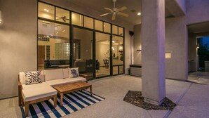 An outdoor seating area with a sofa, coffee table, and striped rug.