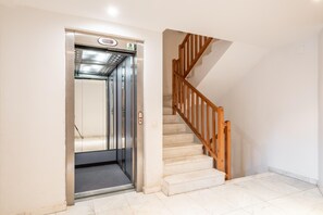 Ein Aufzug mit Bedienfeld und eine Holztreppe mit Handlauf.
