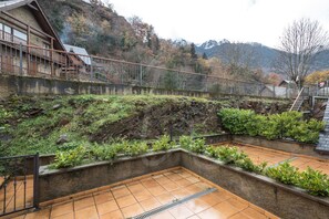 A terraced garden with a wooden deck and a metal railing.