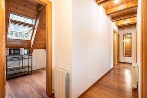 Ein modernes Interieur mit Holzbalken, einem Oberlicht, einer Küchenzeile mit Geräten und einem Flur, der zu einer Tür führt.