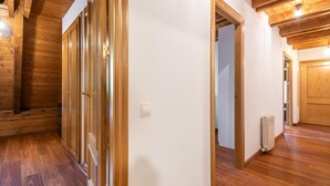 Um corredor com piso de madeira, um radiador e uma porta que dá para outro quarto.