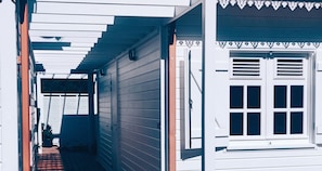 A narrow corridor with wooden walls and a window with shutters.