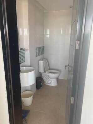 A small, clean bathroom with a toilet, sink, and a trash bin.