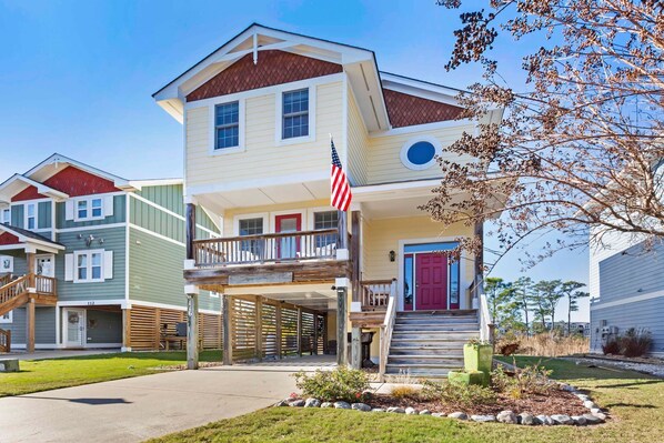 Ein zweistöckiges Wohnhaus mit einer Veranda, einer roten Tür und einer US-amerikanischen Flagge.