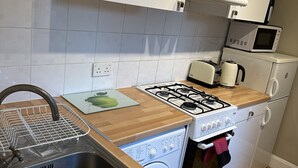 A compact kitchen with a sink, stove, microwave, and built-in oven. - Quiet Paddington studio Apartment (London)