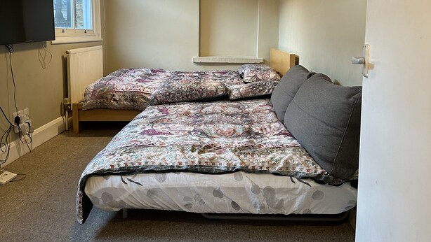 A bedroom with a bed, two pendant lights, a window, and a radiator. - Quiet Paddington studio Apartment (London)