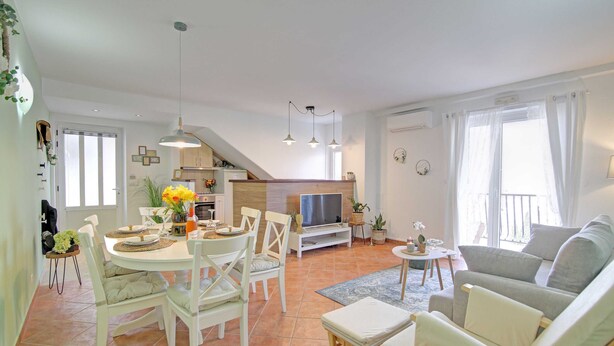Ein geräumiger Wohnbereich mit Esstisch, Stühlen, einer Couch und einem Fernseher.