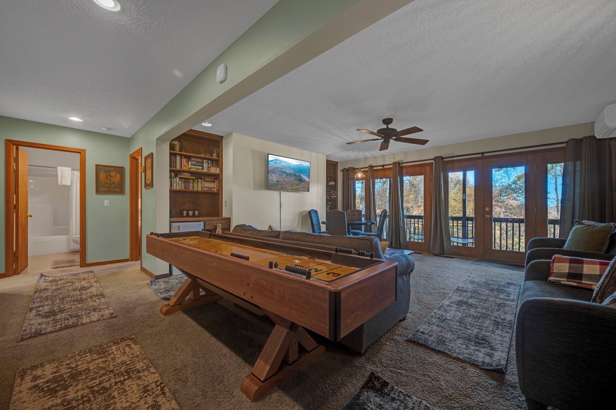 A spacious living room with a pool table, a sofa, and a television.