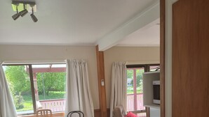 A kitchen with a dining area, featuring a table with chairs, a cabinet with drawers, and a microwave on the counter. - The Pink House (Tokoroa)
