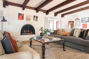 Una sala acogedora con chimenea, un sofá, una mesa de centro y una estantería.