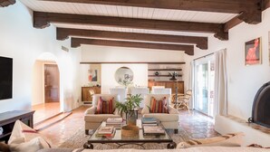 A spacious living room with a fireplace, a television, and a dining area with chairs and a table. - Charming 5BDR Hacienda w/ Pool, Fire Pit, Billiards | La Casona by AvantStay (Phoenix)
