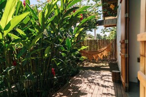 A wooden deck with a hammock and lush greenery. - Casa Canoa (Maraú)
