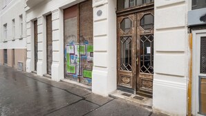 Un edificio con fachada blanca, puerta de madera con persiana cerrada y un gran ventanal con el número 35 a la derecha.