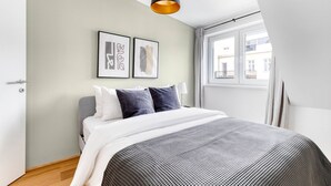 Un dormitorio moderno con una cama, un ventanal y dos cuadros enmarcados en la pared.