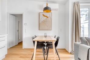 Un comedor moderno con una mesa de madera y sillas negras, una lámpara colgante y un cuadro en la pared.
