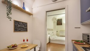 A compact kitchen with a dining area, a bed visible through an open door, and a chalkboard menu. - L'Antica Concia di Santa Croce - Sweet Dreams in Florence (Firenze)