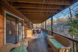Relax on the deck with a hot tub and comfortable seating area overlooking the wooded landscape.