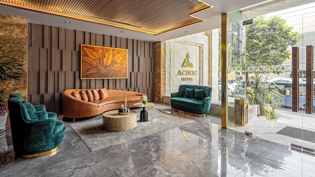 Un hall d’hôtel moderne avec un canapé en cuir aux lignes courbes, un fauteuil turquoise et une table basse ronde.