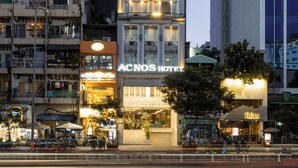 Un hôtel à plusieurs étages doté de balcons, avec une enseigne de restaurant bien visible, et un bâtiment moderne situé à côté.
