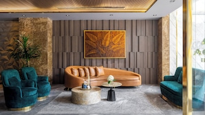 Un salon moderne avec un canapé aux lignes courbes, des fauteuils turquoise et une table basse ronde.