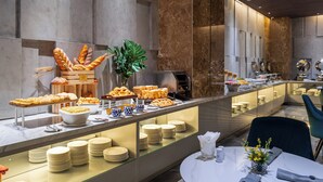 Un buffet proposant une variété de plats et un espace repas avec une table dressée pour deux personnes.