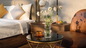 Une chambre à coucher moderne avec un lit, une table de chevet en bois, une table en verre et un fauteuil en cuir.