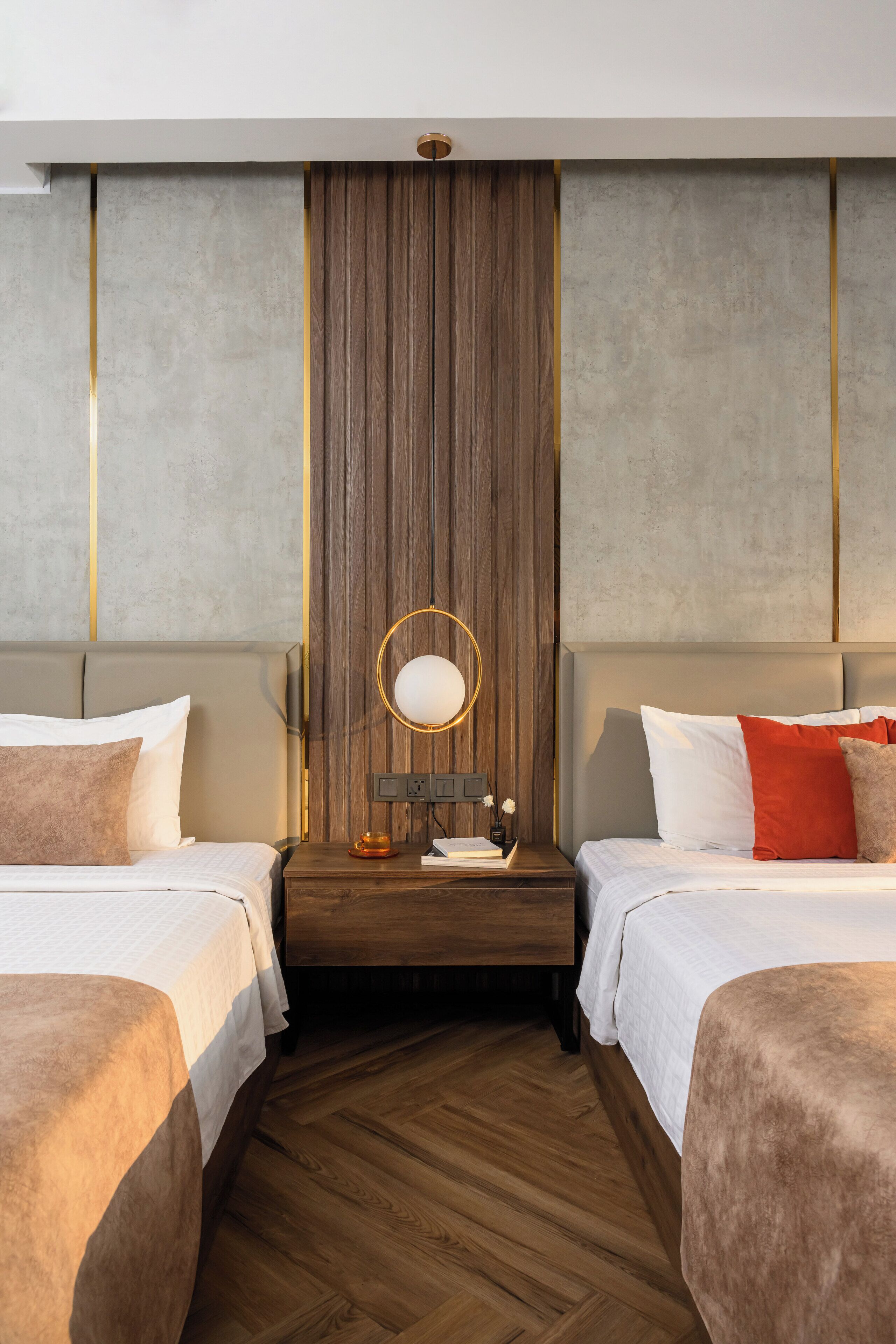 A hotel room with two beds, a wooden floor, a large mirror, and a modern design.