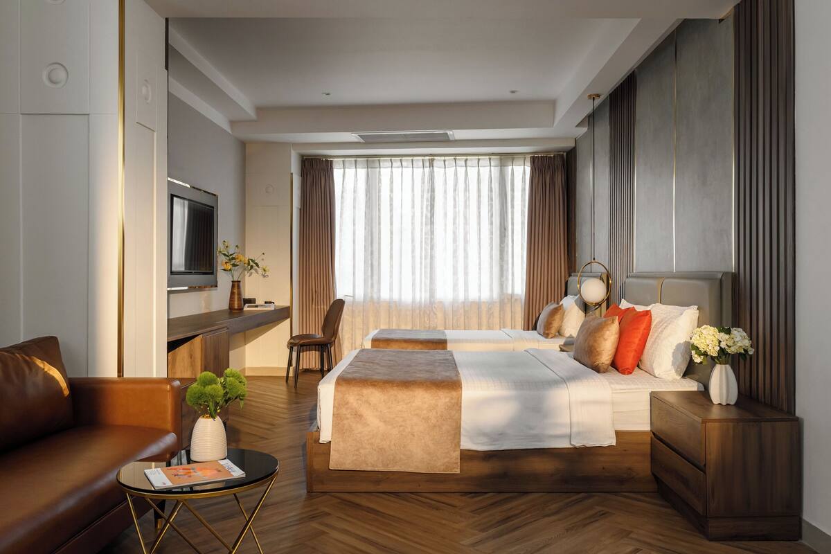 Une chambre d’hôtel moderne avec un grand lit, un canapé, une télévision et un bureau.