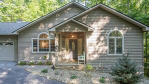 A single-story house with a stone foundation, a front porch, and a driveway. - Hummingbird Hideaway in Connestee Falls (Brevard)