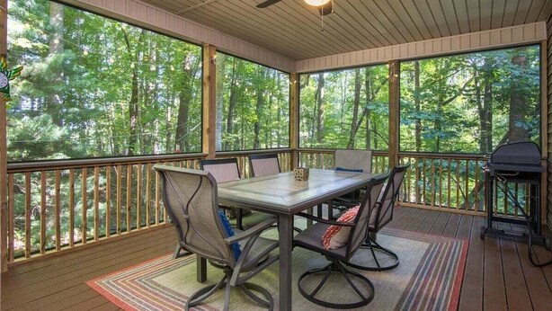 A covered outdoor deck with a table and chairs, a ceiling fan, and a grill. - Hummingbird Hideaway in Connestee Falls (Brevard)