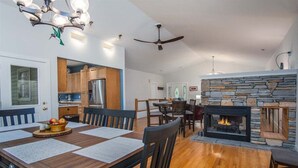 A dining area with a wooden table, chairs, and a fireplace. - Hummingbird Hideaway in Connestee Falls (Brevard)