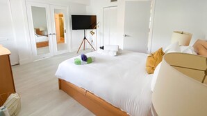 Une chambre d’hôtel avec un grand lit, un téléviseur posé sur un meuble, une armoire et une table de chevet.