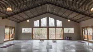 Un grand espace intérieur doté de larges fenêtres, d’un plafond haut et de tapis de sol pour la pratique d’exercices.