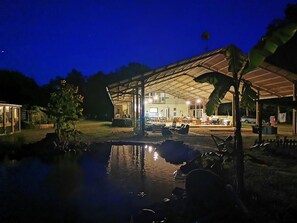 Relax by the pool in a serene outdoor setting surrounded by lush greenery and a covered seating area.