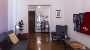 Un salon moderne avec un canapé, un fauteuil et un téléviseur à écran plat fixé au mur.