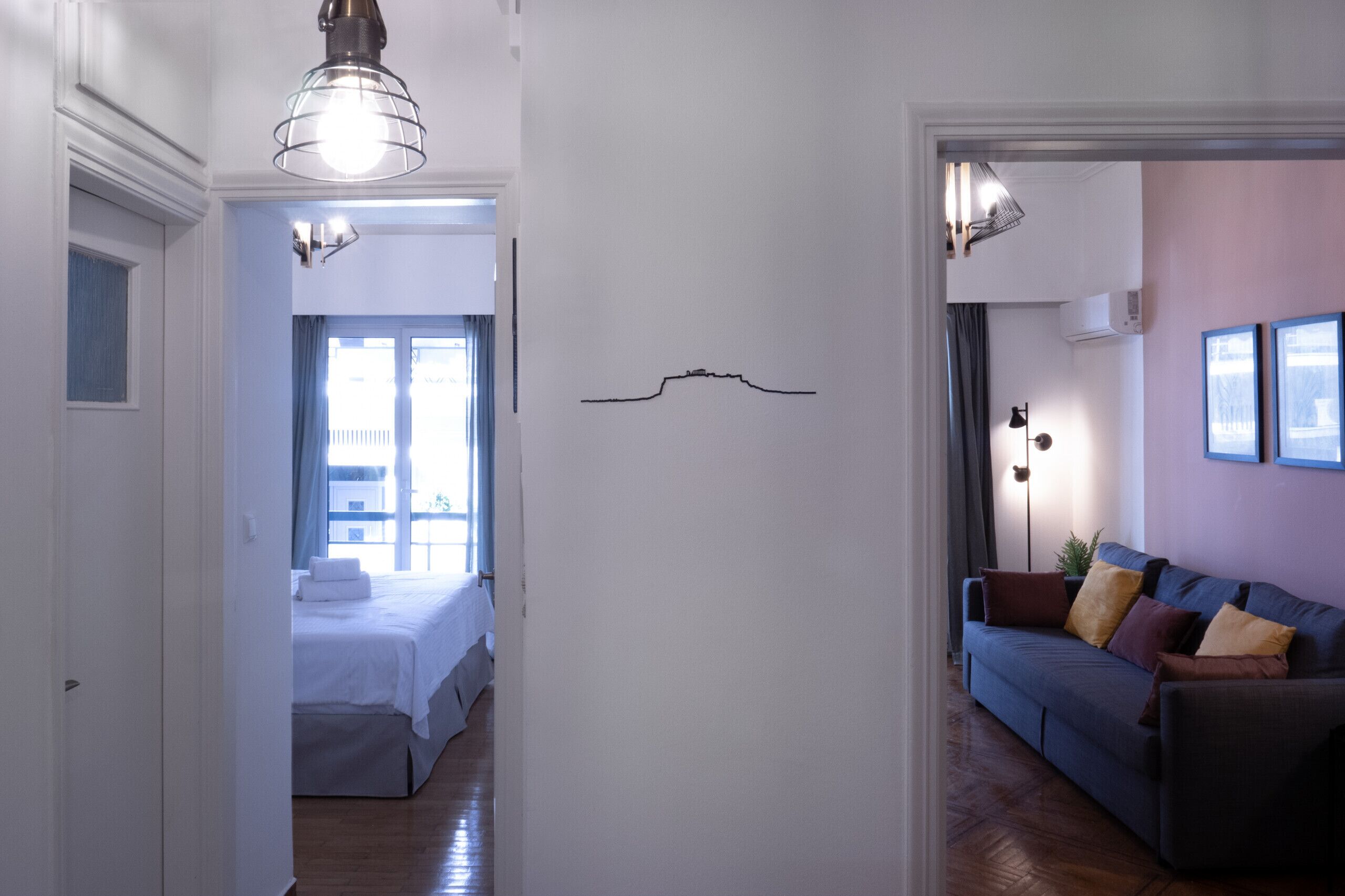 A hotel room with a bed, a sofa, and a wall-mounted light fixture.
