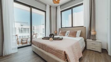 A modern bedroom with a large bed, a nightstand, and a view of the city through large windows.