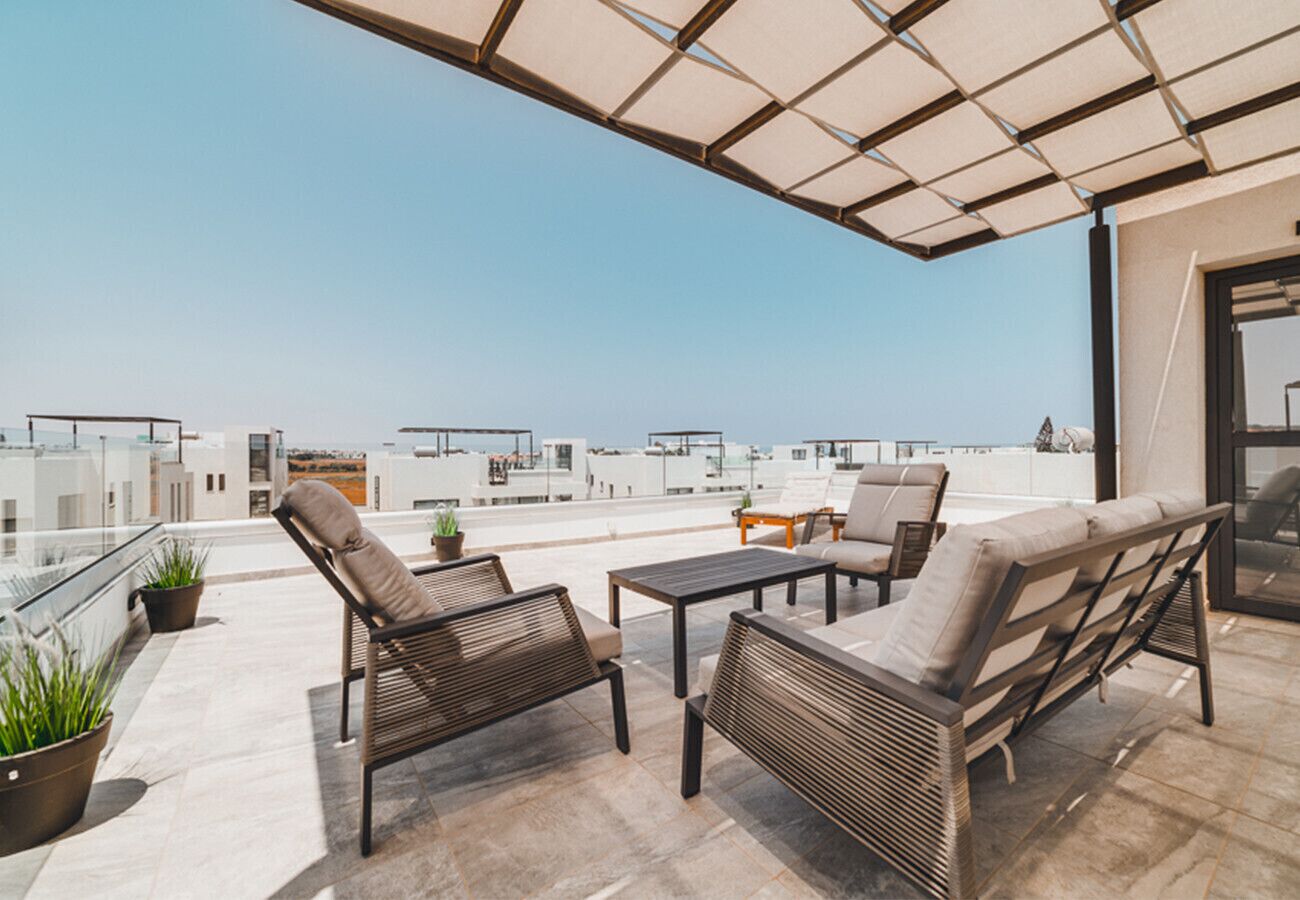 A rooftop terrace with outdoor furniture, potted plants, and a view of the cityscape.