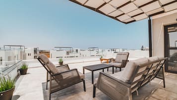 A rooftop terrace with outdoor furniture, potted plants, and a view of the cityscape.