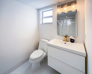 Een moderne badkamer met toilet, wastafel en spiegel.