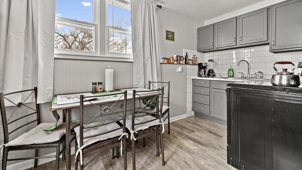 A kitchen with a dining table, chairs, cabinets, and a black refrigerator.