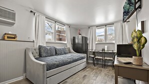 A compact living space with a sofa, a dining table, a TV, and a refrigerator.