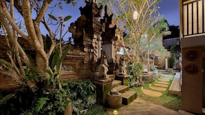 Un templo balinés tradicional con estatuas de piedra, exuberante vegetación y un sendero de jardín cuidado.