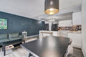 A modern kitchen with white cabinets, a black refrigerator, and a dining area with a dark table and chairs. - 3bd_cj_12 (Breckenridge)