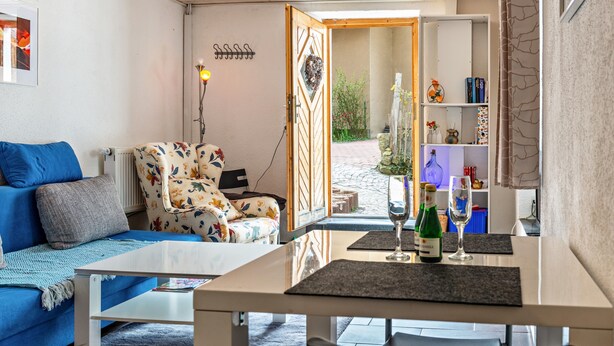 A living room with a sofa, armchair, table, and a bookshelf.